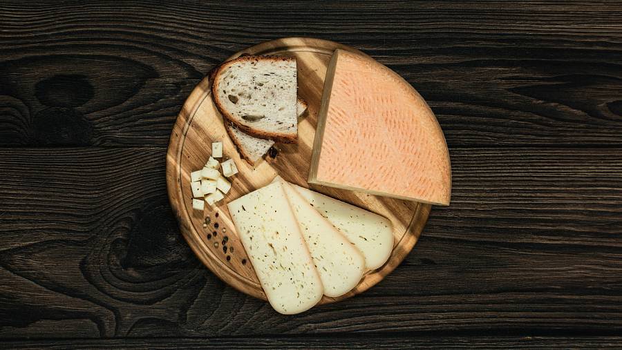 Alpbachtaler Bierkäse mit Brotscheiben auf einem Holzbrett